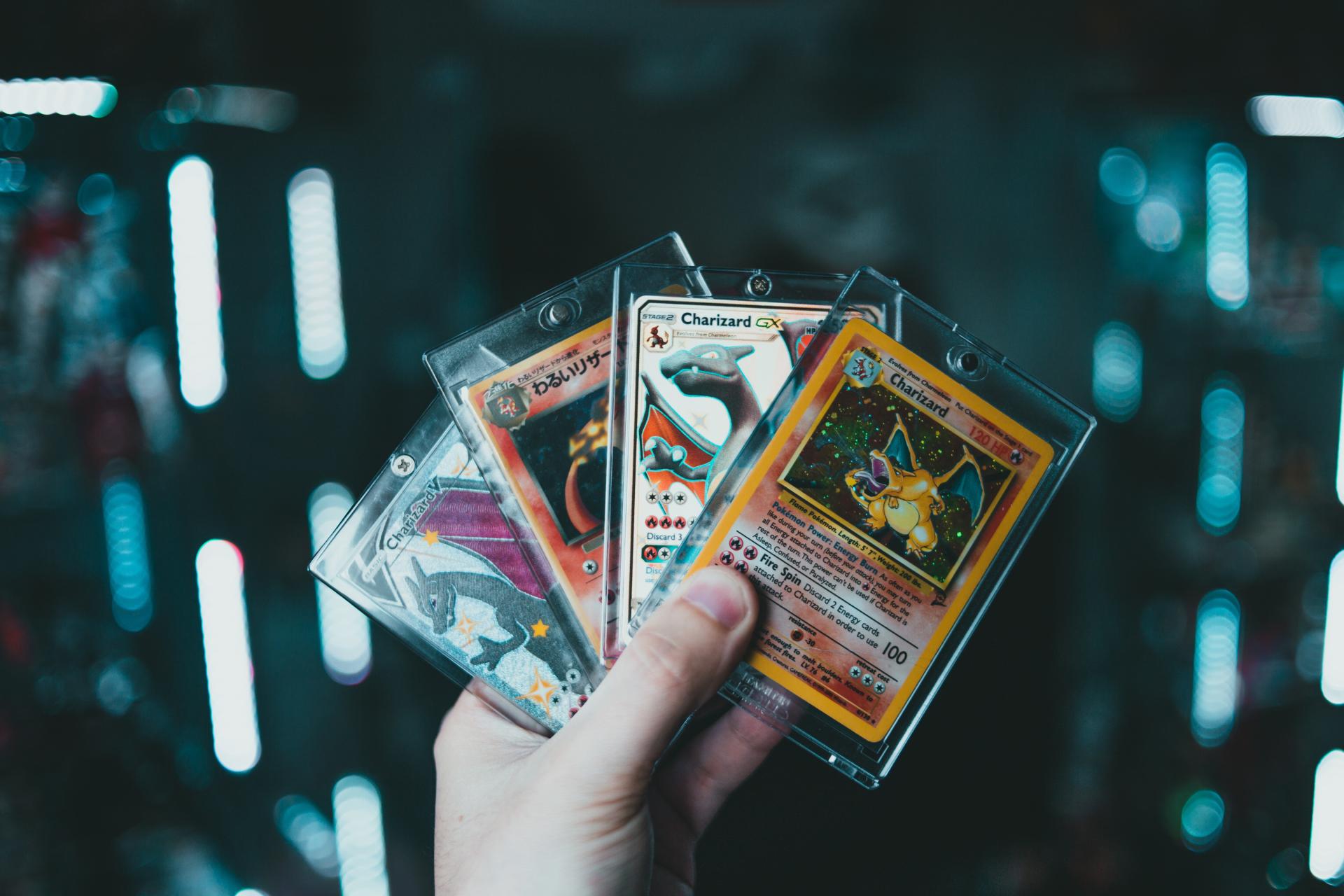 A person's hand holding 4 pokemon cards